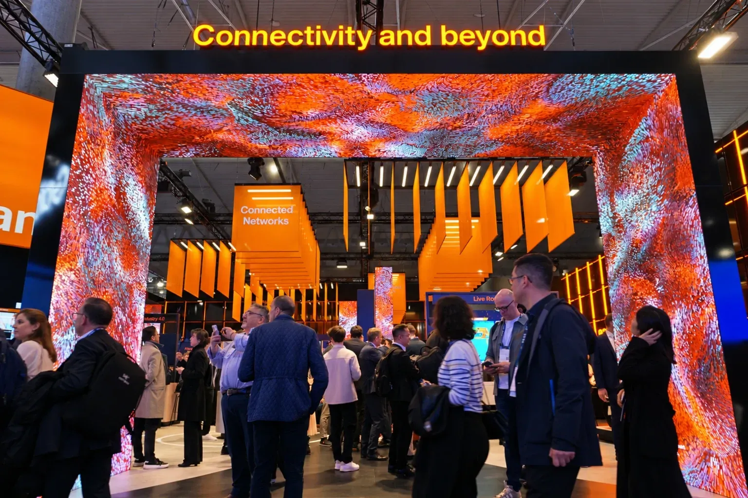Visitors beneath the Orange MWC25 illuminated gateway